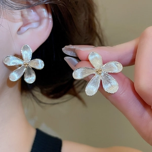 Dettaglio macro dell'orecchino a fiore in argento spazzolato con perle dorate