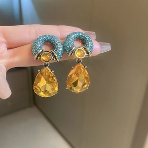 Macro shot of vintage gold earrings with blue pave crystals and yellow pear-cut drops