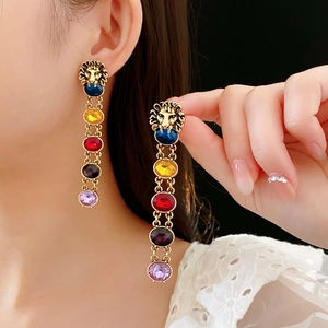 Vue détaillée de boucles d'oreilles tête de lion dorées avec franges de pierres colorées