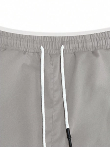 Detail of grey joggers featuring elastic waistband and adjustable white drawstring cord