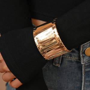 Detailed view of a wide golden cuff bracelet with multi-layer horizontal textures