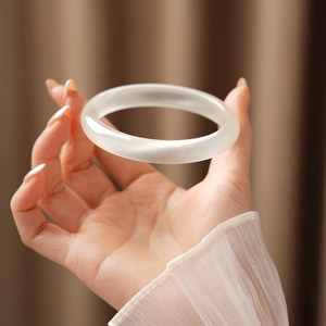 Close-up of translucent matte white cat eye stone bangle with elegant chiffon sleeve