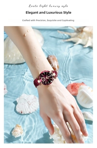 Detail of rose gold ladies watch with faceted glass and wine red leather strap on water background