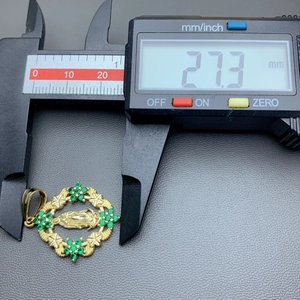Macro view of a gold pendant with green zircon being measured by a digital caliper 27.3mm