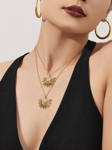 Gros plan sur le collier pendentif tournesol doré en zircone et les grandes créoles portés