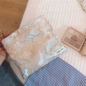 Macro detail of elegant beige rose jacquard fabric makeup bag with simple wish label
