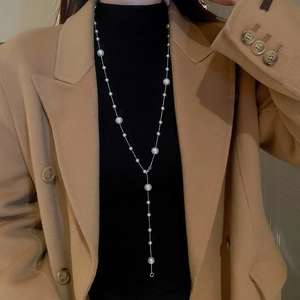 Close-up of long gold-plated Y-necklace with irregular pearls and elegant tassel detail