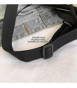 Détail de la bandoulière réglable en nylon noir d'un sac en denim avec boucle en plastique