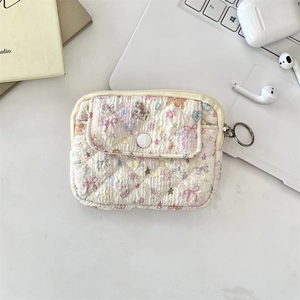 Close-up of floral quilted mini storage bag with metal zipper and ring buckle on desk