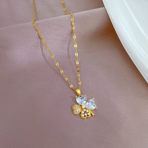 Detail of clover pendant with gold chain featuring heart-shaped crystals and micro-pavé