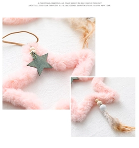 Detailed view of pink faux fur star ornament with wooden beads and white feathers