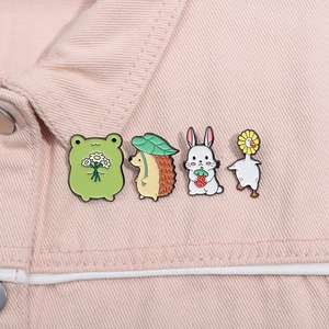 Détail de quatre épingles en émail d'animaux mignons sur une veste en jean rose