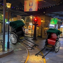 Detail of vintage rickshaw models in red and green with realistic spoke wheels