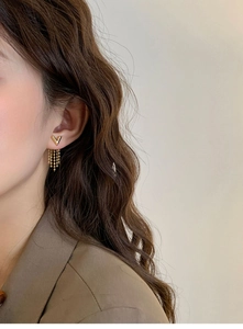 Close-up of elegant V-shaped gold chain tassel earrings worn by a female model