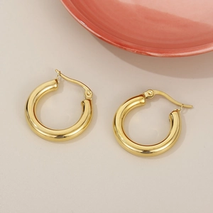 Close-up of golden stainless steel hoop earrings with polished finish and clasp detail
