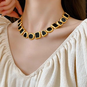 Close-up of vintage gold geometric necklace with black enamel inlay on female model