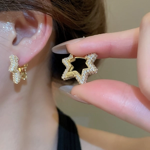 Close-up of gold star-shaped earrings with clear zircons and snap-on clasp detail