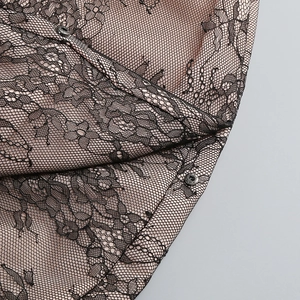 Detailansicht der schwarzen Spitze mit rosa Futter und Metalldruckknöpfen am Kleidsaum
