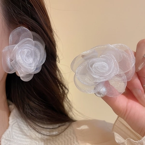Detailed macro view of white organza rose earrings with pearls and silver studs
