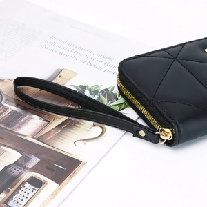 Detail of black quilted leather wallet with gold zipper and matching wrist strap
