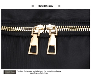 Close-up of premium gold-tone dual zippers on a durable black nylon backpack detail