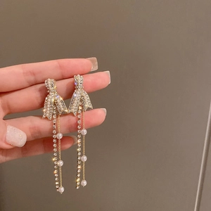 Détail de boucles d'oreilles nœud doré avec cascades de perles et de longs pompons