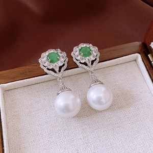 Macro shot of a vintage silver floral earring with a green gemstone and white pearl