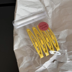 Detailed view of four hollow yellow hairpins in a clear Hansy made branded package