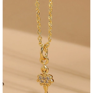Close-up of gold key pendant with sparkling zircon accents on a delicate chain necklace