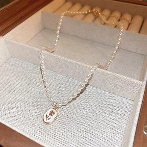 Detail of a pearl necklace with flower pattern gold pendant inside a wooden box