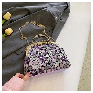 Detail of floral embroidery on purple shell bag with golden metal frame and chain