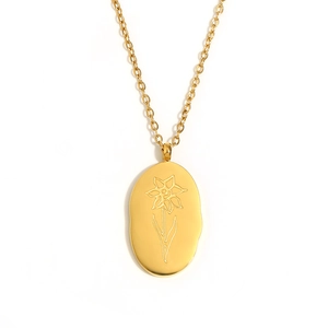 Golden oval pendant necklace with daffodil flower engraving on a delicate cross chain