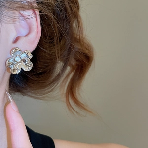 Close-up of polished silver flower stud earrings worn on model for a trendy chic style