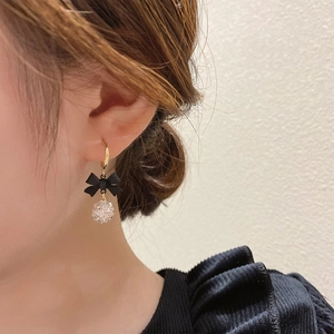 Elegant C-shaped bow earrings with sparkling zircon sphere worn by a female model