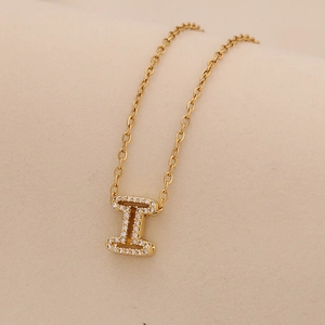 Close-up of golden letter I pendant with sparkling pavé crystals on a delicate chain
