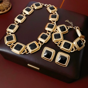 Vintage jewelry set featuring gold-toned square links with black enamel on a display box