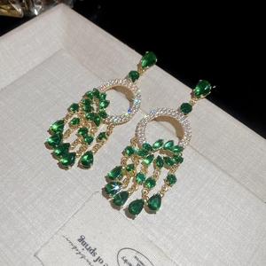 Détail de boucles d'oreilles style cour française avec cristaux verts et reflets étoilés