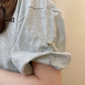 Detail of T-shirt sleeve with decorative metal ball and chain magnetic clip for styling
