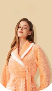 Detail of soft peach coral fleece bathrobe with waffle texture and white piped collar