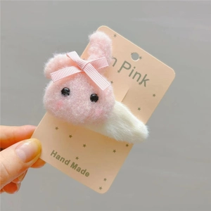 Close-up of a cute plush rabbit hair clip in pink and white on a decorative card