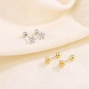 Mini floral screw back earrings in gold and silver finish on white linen fabric