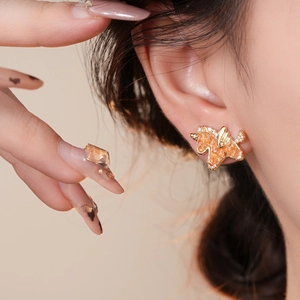 Detailed view of a golden unicorn stud earring with amber stones and white crystals on ear
