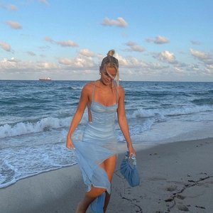 Detail of light blue backless slit dress with matching handbag at beach sunset