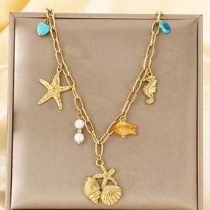 Gros plan d'un collier en acier doré avec pendentifs étoile de mer, coquillage et perle
