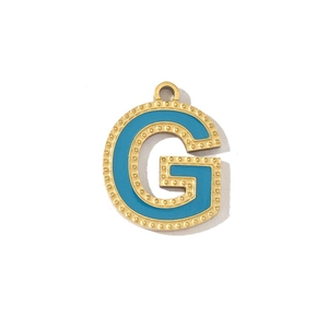 Detail of a vintage gold letter G pendant with blue enamel and dotted edge texture