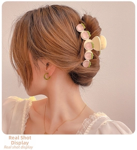 Detail of a cream hair claw clip with pink peach accents worn on a woman's hair