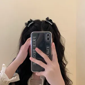 Detail of elegant black ribbon bow hair clips with white pearls worn on hair side