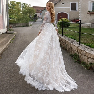 Elegant white lace wedding dress featuring a deep V-back and long lace sleeves with a long train
