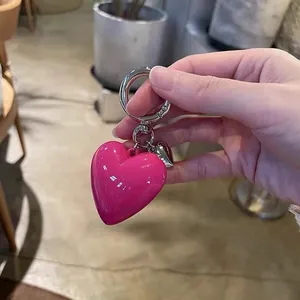 Close-up of glossy rose pink heart charm with silver spring clasp for handbags