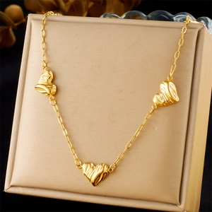 Detailed view of triple heart pendants on a gold O-chain necklace in a jewelry box